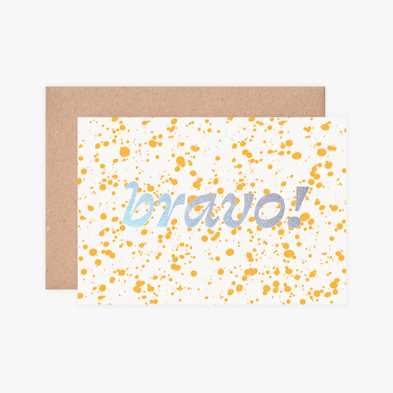 Greeting card with 'bravo!' text and yellow confetti on a white background, accompanied by a brown envelope.