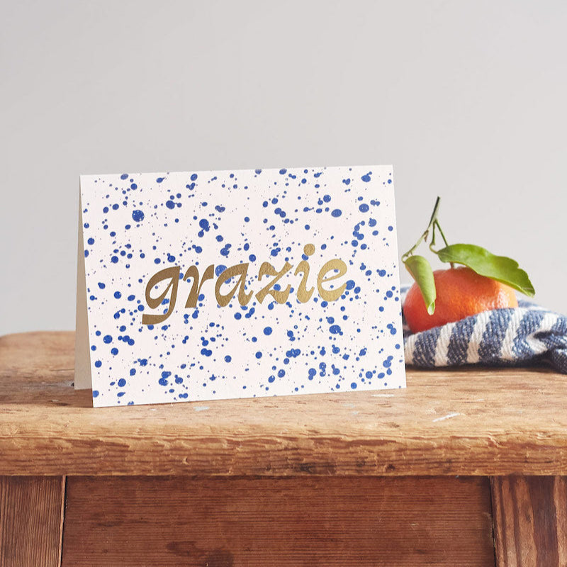 Greeting card with 'grazie' text on a wooden surface with a blurred background